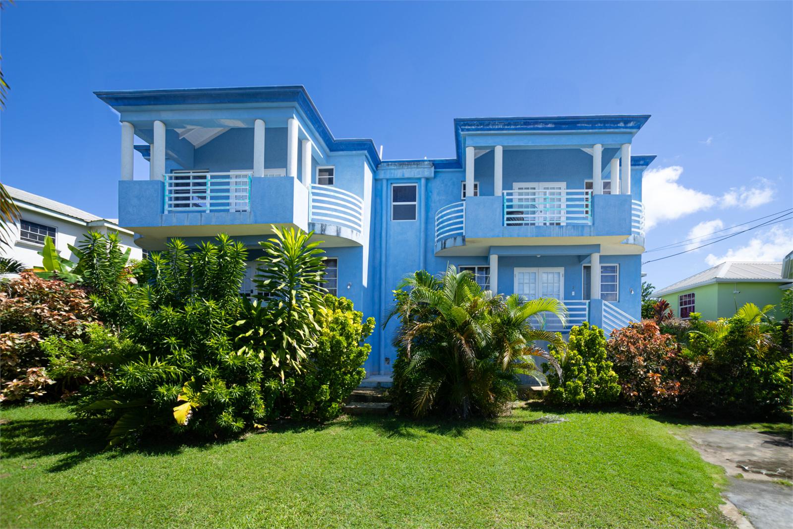 Blue Best E Villas building with a lawn and tropical planting
